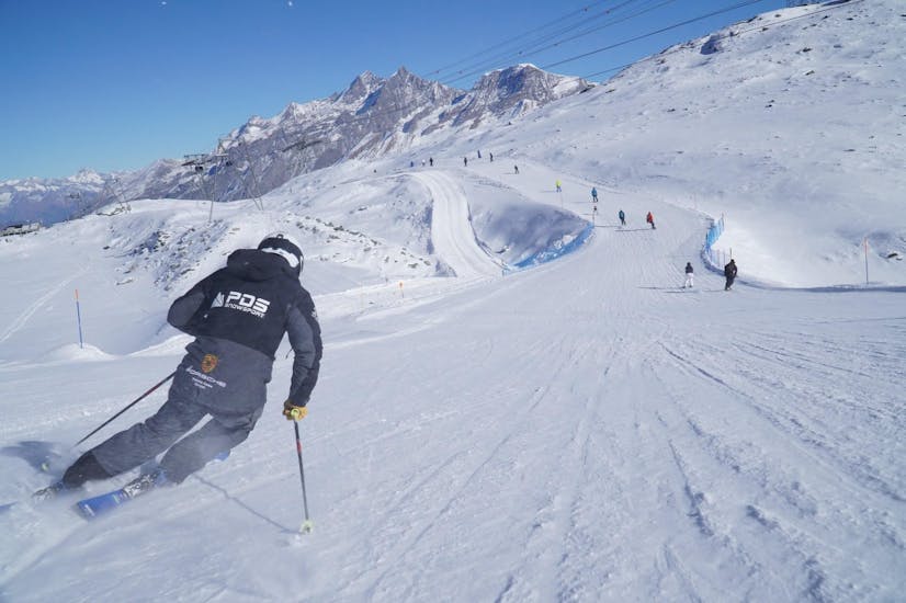 Ein Skifahrer rast während einem Skikurs für Erwachsene mit der Skischule PDS Snowsports die Piste hinunter.