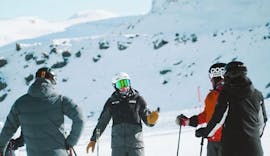 Volwassenen luisteren aandachtig naar hun instructeur tijdens hun skilessen voor volwassenen bij PDS Snowsports skischool.