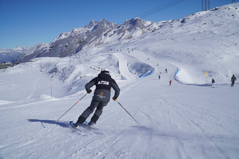 Un skieur fait une course de descente pendant ses cours de ski privés pour adultes avec l'école de ski PDS Snowsports.