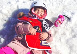 A little girl laughs in the snow during kids ski lessons at the G'Lys La Lécherette-Les Mosses snow garden.