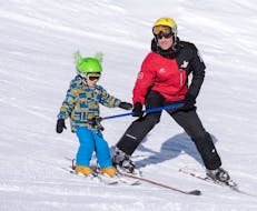 An instructor from G'Lys La Lécherette-Les Mosses supervises a young skier for his first snowplough during private kids ski lessons.