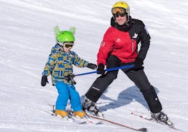 Ein Skilehrer von G'Lys La Lécherette-Les Mosses beaufsichtigt einen jungen Skifahrer bei seinem ersten Schneepflug während des privaten Kinder-Skikurses. 