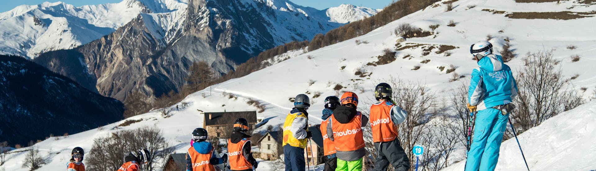 Pendant un cours de ski pour enfants de l'ESI Ski Family un groupe d'apprentis skieurs fait une pause sur les pistes du Grand Bornand.