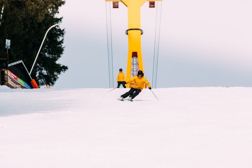 Ein Skifahrer fährt eine Piste runter im Skikurs für Erwachsene aller Levels.