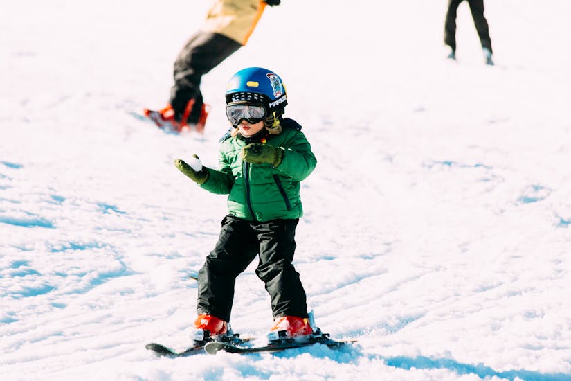 Ein glückliches Kind übt den Schneepflug während des Privatskikurses für Kinder aller Könnerstufen bei Native Snowsports Oberwiesenthal.