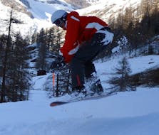 Een snowboarder maakt een sprong tijdens privé snowboardlessen vanaf 5 jaar voor alle niveaus bij de skischool G'Lys Les Paccots.