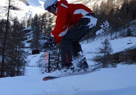 Un snowboard fait un saut pendant un cours particulier de snowboard dès 5 ans pour tous niveaux avec l'école de ski G'Lys Les Paccots.