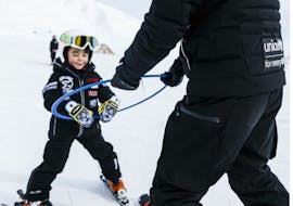 A child is guided on the slopes by an instructor from the Giorgio Rocca Ski Academy during kids ski lessons (4-6 y.) for beginners. 
