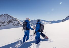 A skier and a snowboarder enjoy the view during their private ski tour with the Skipower Finkenberg ski school.
