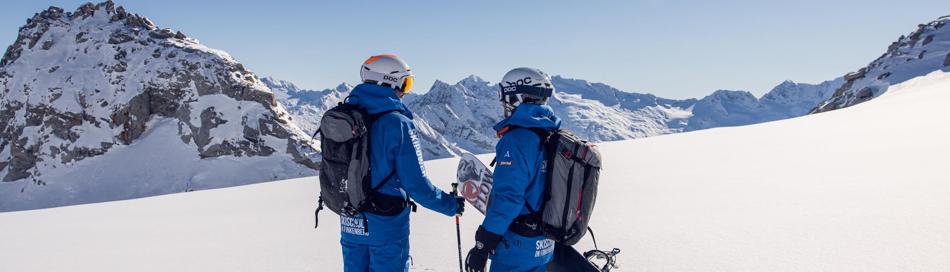 A skier and a snowboarder enjoy the view during their private ski tour with the Skipower Finkenberg ski school.