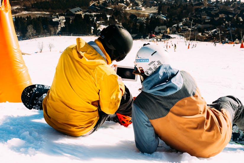Ein Lehrer von Native Snowsports Oberwiesenthal erklärt einem Schüler etwas während des privaten Snowboardunterrichts für Kinder und Erwachsene aller Könnensstufen.