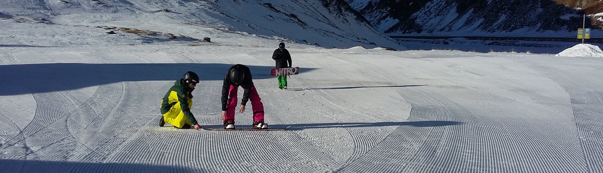 Un maestro di snowboard della scuola di sci Snowlimit Andermatt mostra ai suoi allievi vari esercizi durante un corso di snowboard per bambini.