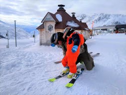 Un maestro di sci della scuola Snowlimit Andermatt aiuta un piccolo sciatore durante le sue lezioni private di sci per bambini e ragazzi.