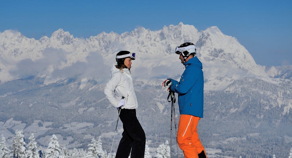 Twee skiërs genieten van het uitzicht tijdens hun skilessen voor volwassenen met de Schneesportschule Oberndorf.