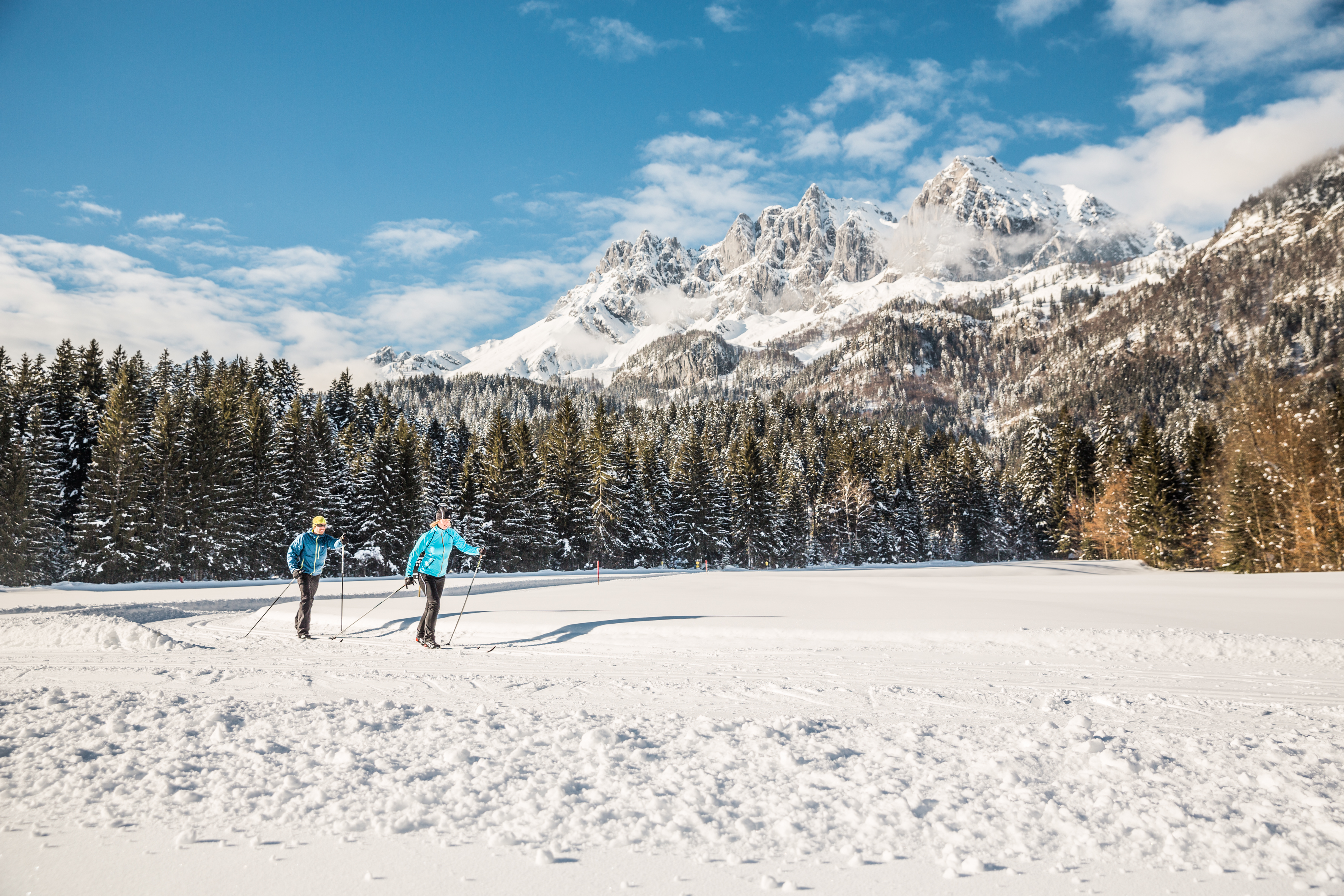 Two cross-country skiers enjoy the nature during the cross-country skiing lessons for all levels with the Schneesportschule Oberndorf.