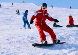 A snowboarder rides down the slopes during his private snowboarding lessons for kids and adults of all levels with the Schneesportschule Oberndorf.