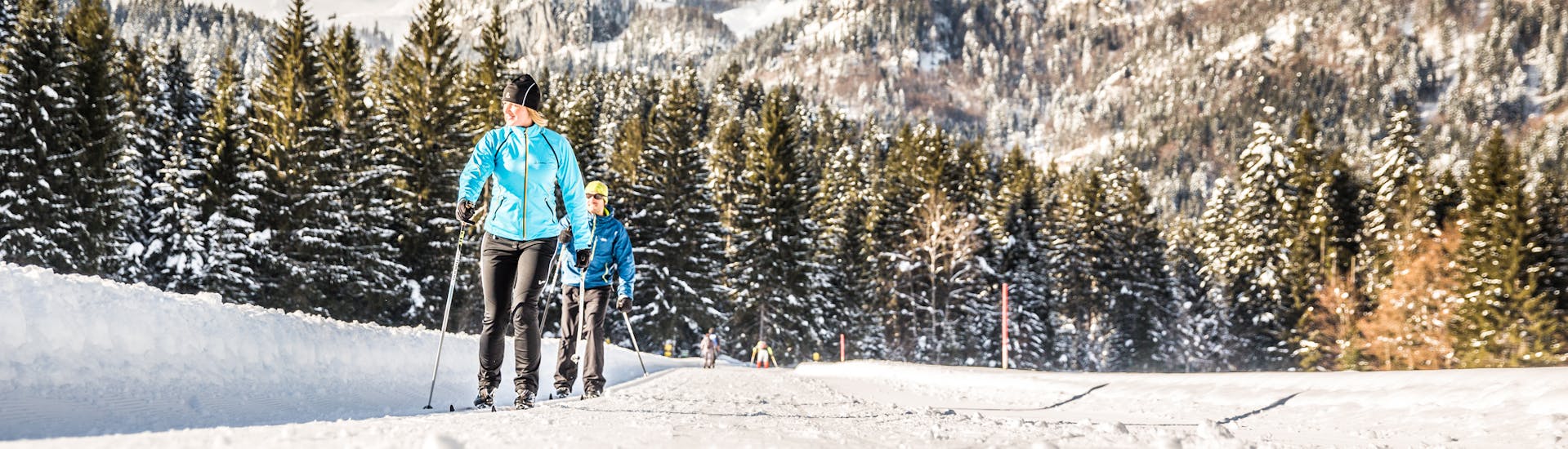 Two cross-country skiers enjoy the fresh air and nature during their private cross-country skiing lessons with the Schneesportschule Oberndorf. 