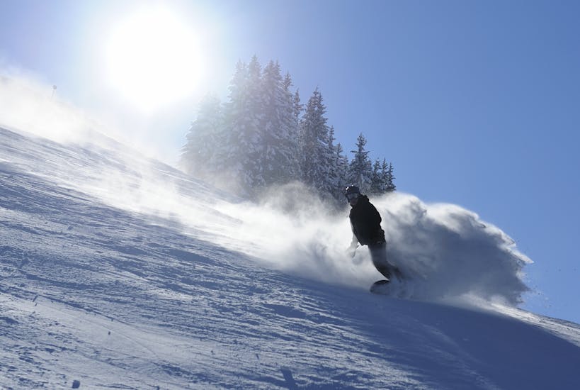 Ein Snowboarder rast während dem Snowboardkurs für Kinder und Erwachsene für fortgeschrittene Snowboarder mit der Schneesportschule Oberndorf die Piste hinunter.