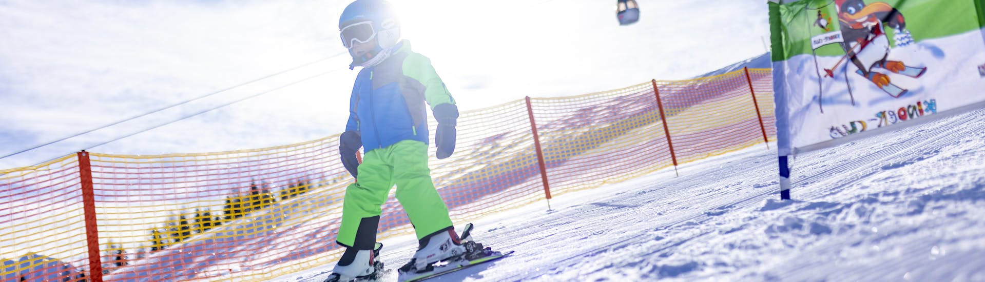 Een kleine skiër daalt de helling in het Kinderland af tijdens een skiles voor kinderen en tieners voor beginners met de Nassfeld Skischool.