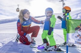 A ski instructor from the Nassfeld Ski School looks after two little skiers during ski lessons for kids and teens for beginners.
