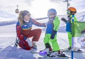 A ski instructor from the Nassfeld Ski School looks after two little skiers during ski lessons for kids and teens for beginners. 