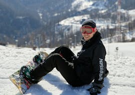A snowboarder sits in the snow during his snowboarding lessons for kids and adults for beginners with the Nassfeld Ski School.