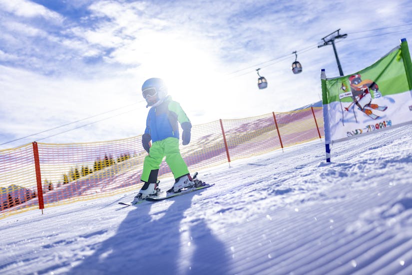 Ein kleiner Skifahrer fährt während seinem privaten Skikurs für Kinder aller Altersstufen mit der Skischule Nassfeld die Piste hinunter.
