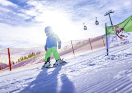 A little skier descends the slope during a ski lesson for kids and teens for advanced skiers with the Nassfeld Ski School.  