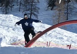 Een gevorderde snowboarder doet een kunstje tijdens zijn snowboardlessen voor kinderen en volwassenen bij de Nassfeld Skischool.