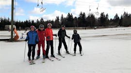 A group of skiers take a photo with their ski instructor from the Skischule Sahnehang during their adult ski lessons for all levels.