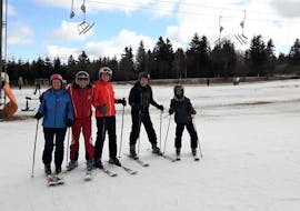 A group of skiers take a photo with their ski instructor from the Skischule Sahnehang during their adult ski lessons for all levels.