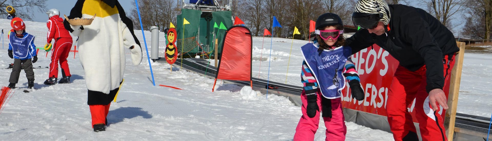 Ein Skilehrer von der Skischule Sahneberg zeigt einem kleinen Mädchen während dem privaten Skikurs für Kinder und Jugendliche für alle Levels einige Übungen.