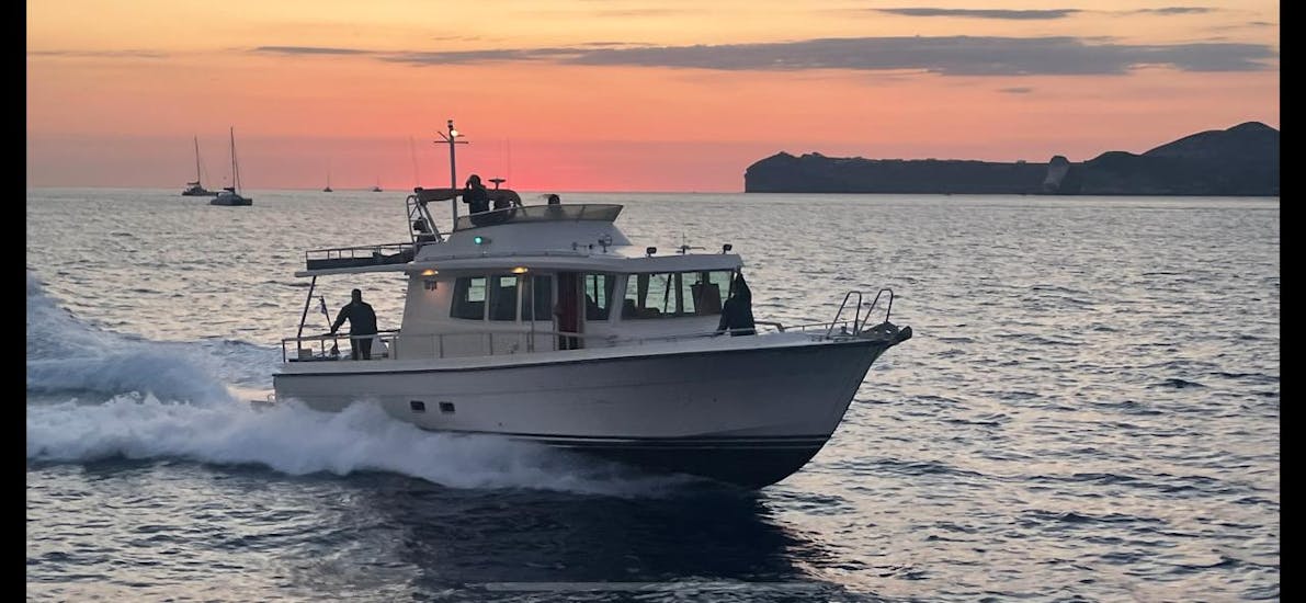 Ein Boot im Meer vor dem Sonnenaufgang während der Privaten Targa -Motoryachttour um die Insel Thirasia mit BBQ & Transfer.