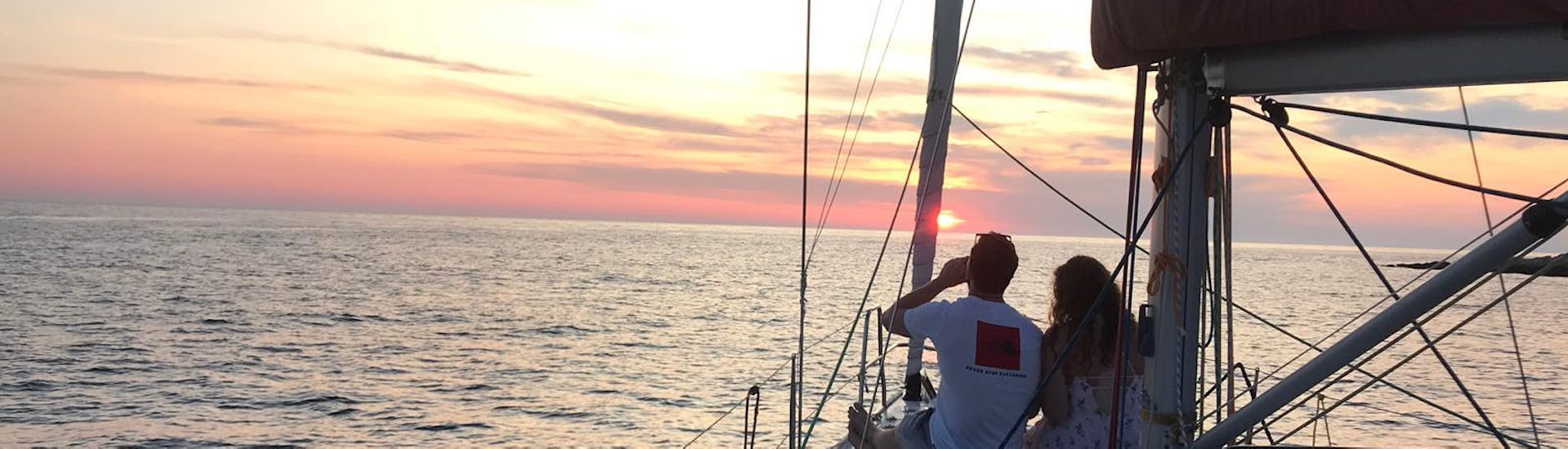 Des personnes regardent le coucher de soleil pendant la balade romantique privée au cap Pelegrin en voilier à partir de Hvar organisée par The Day Sail.