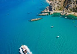 A boat is sailing on the crystal water in during one of the boat trips from Tropea to Capo Vaticano - Sunset tour.