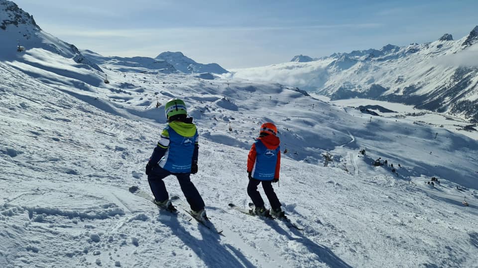 Zwei Kinder genießen das Bergpanorama während ihres Kinder-Skikurs (6-12 J.) für Fortgeschrittene mit Silvaplana Top Snowsports Corvatsch.