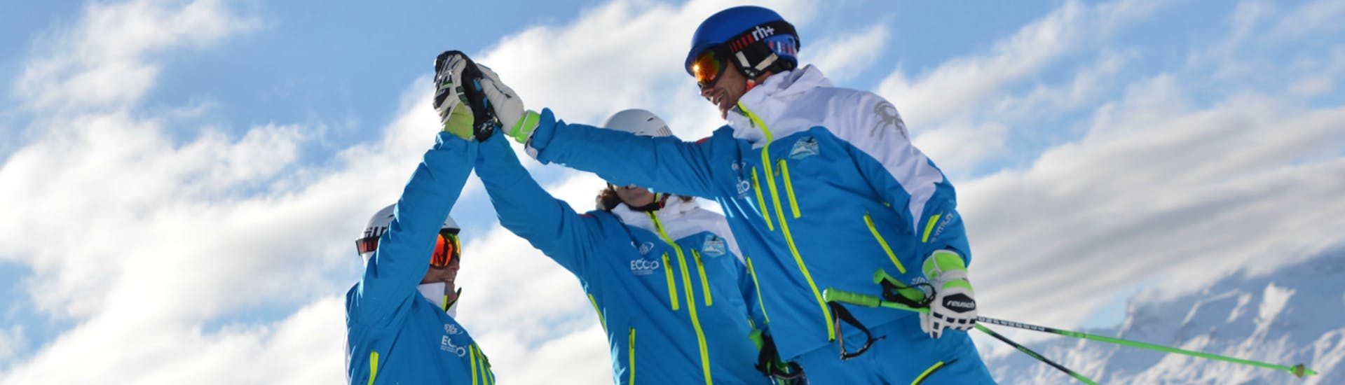 Three ski instructors from the Silvaplana Top Snowsports ski school give each other a high-five during the kids ski lessons for advanced skiers..