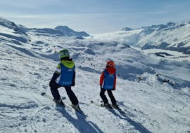 Two kids are admiring the mountain panorama during their Kids Ski Lessons (6-12 y.) for Advanced Skiers with Silvaplana Top Snowsports - Corvatsch.