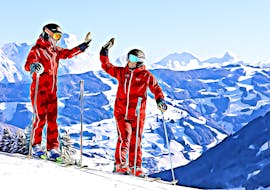Two instructors giving each other a high five during Private Ski Lessons for Adults "SkiLL - The Rockstars of the Instructors" in Saalbach Hinterglemm.