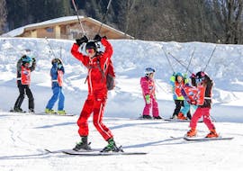 Een skileraar geeft les aan beginnende skiërs tijdens de skilessen voor beginnende skiërs "SkiLL Happy Kids" - 5 tot 14 jaar bij skiLL Saalbach Hinterglemm. 