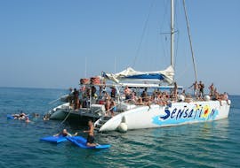 Mensen zwemmen naast de boot van Catamaran Sensations Barcelona tijdens een Catamaran Boottocht met BBQ rond Barcelona.