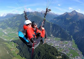 Een klant en zijn piloot van AIRflow Tandem Paragliding genieten tijdens hun Classic Plus vlucht in het Zillertal van het uitzicht op de bergen.
