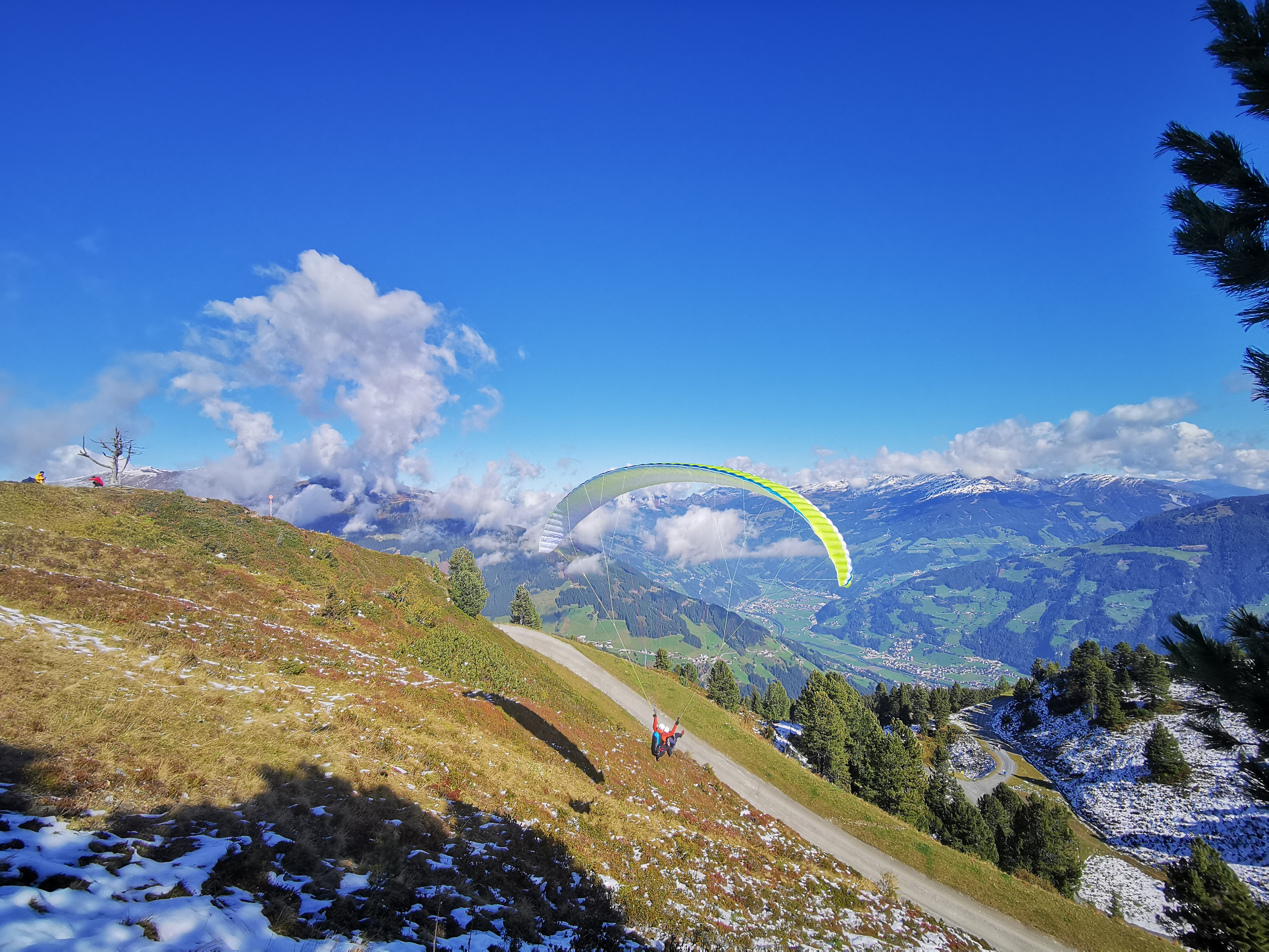 The pilot of AIRflow Tandem Paragliding Zillertal takes off with the customer for his booked tandem paragliding premium flight in a beautiful summer landscape.