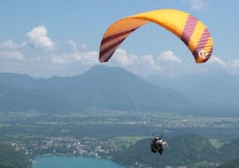 Ein Kunde und sein Pilot von Lake Bled Paragliding Tandem Flights inmitten der Berglandschaft und mit direkter Sicht auf den See.