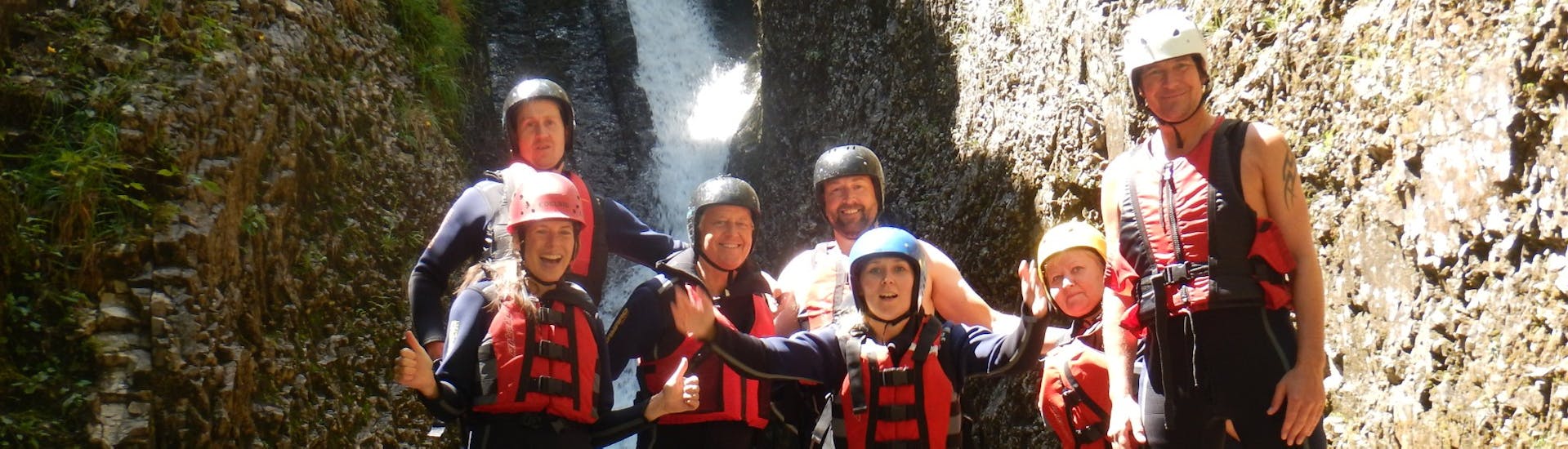 Eine Gruppe von Freunden lachen in die Kamera am Ende ihrer Rafting & Canyoning Tour mit Outdoor Guide Kaiserwinkl. 