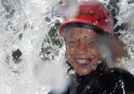 Ein nasses Kind lächelt in die Kamera während des Kindercanyoning in Loferbach mit Outdoor Guide Kaiserwinkl.
