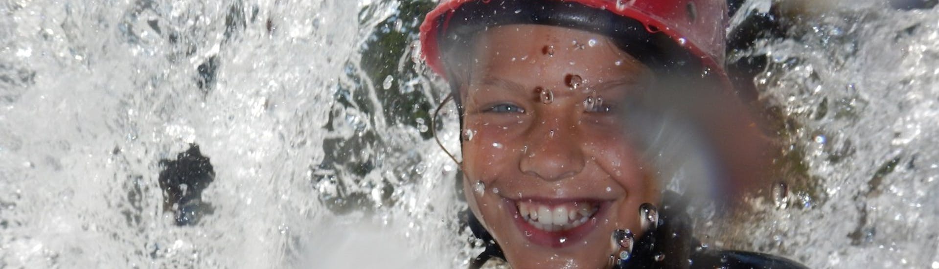 Een nat kind lacht in de camera tijdens Kids Canyoning in Loferbach mit Outdoor Guide Kaiserwinkl.