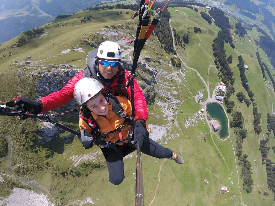 A customer and his pilot from smiling into the camera during Tandem Paragliding from Brunni in Engelberg-Explore with Paragliding Flybypara..