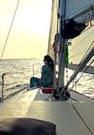 Ein junges Mädchen ruht sich auf dem Deck aus, während der Bootsfahrt bei Sonnenuntergang auf Mallorca ab Port d'Andratx mit Pura Vida Sailing Mallorca.