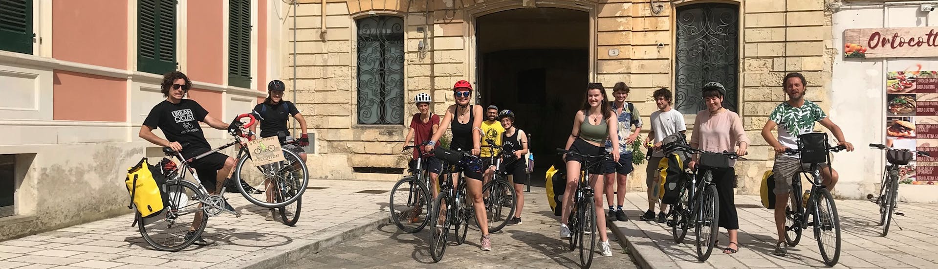 View of a group of bike riders in front off an historical building during the Bike Tour in Lecce with local food tasting with Pugliamare.